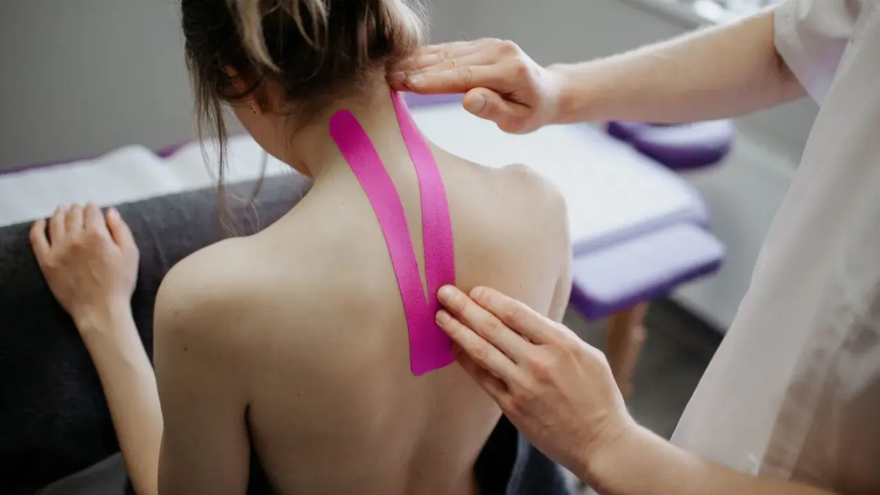 Fizjoterapeuta aplikuje taśmy kinezjotaping na kark pacjentki. Pytanie: czy można masować kręgosłup przy przepuklinie?