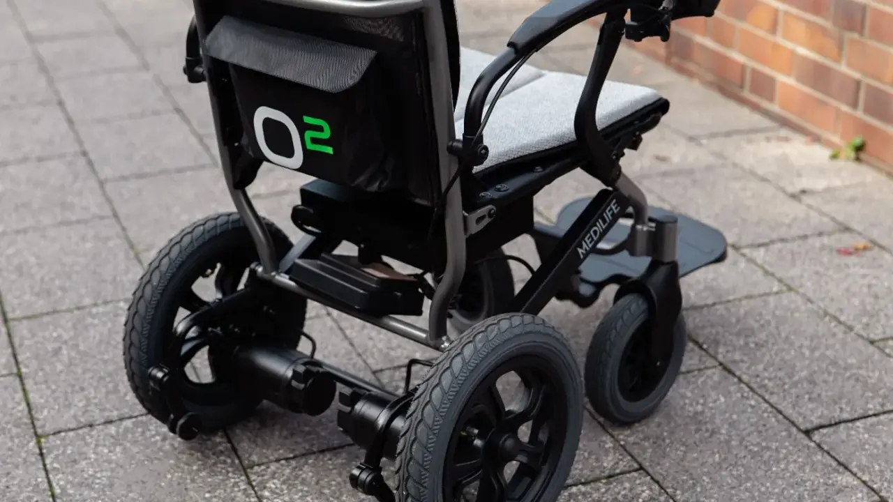 Nowoczesny wózek elektryczny Medilife O2, jeden z wielu rodzajów wózków inwalidzkich, gotowy do jazdy po chodniku.