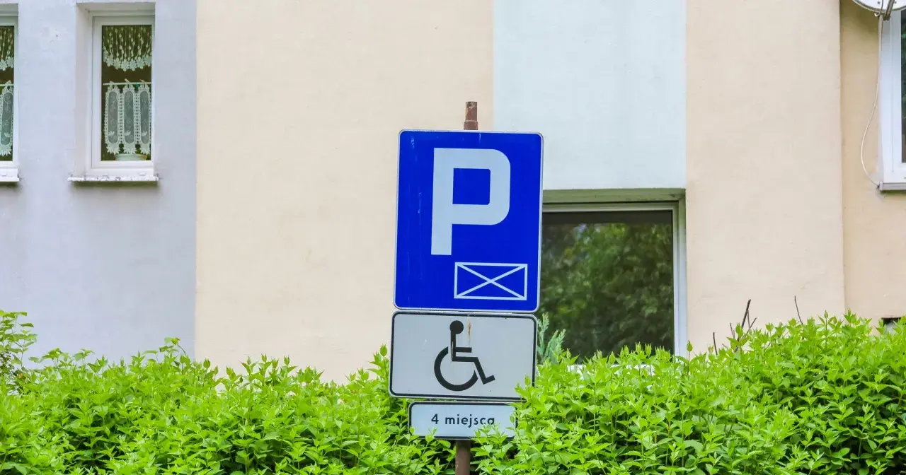 Znak parkingowy dla osób z niepełnosprawnościami, wskazujący 4 miejsca. Informuje o udogodnieniach dla osób z różnymi stopniami niepełnosprawności.
