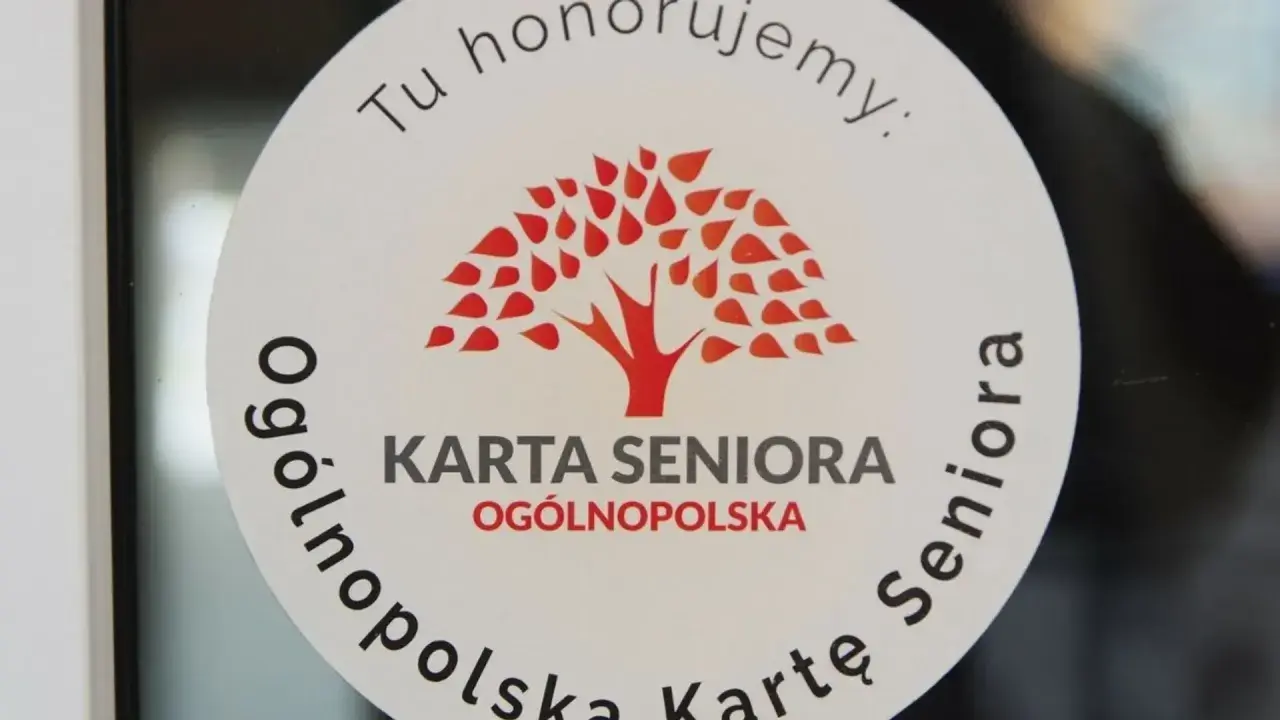 Naklejka z napisem "Tu honorujemy: KARTA SENIORA OGÓLNOPOLSKA" i drzewem. Dostępne zniżki dla posiadaczy ogólnopolskiej karty seniora.