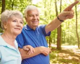 Uśmiechnięty senior od jakiego wieku? Wskazuje drogę podczas spaceru po lesie z ukochaną.