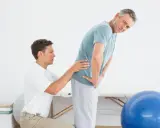 Fizjoterapeuta pomaga mężczyźnie z bólem w dolnej części pleców, ćwicząc mięśnie dna miednicy.