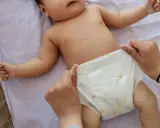 Rączki dziecka leżą na pieluszce, która jest zmieniana. Uważaj na grzybicę pieluszkową.