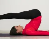 Kobieta wykonuje ćwiczenie "świeca" na macie. To pokazuje, pilates na czym polega – na precyzyjnych ruchach i kontroli ciała.