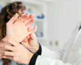 Lekarz bada dłoń pacjenta, który skarży się na bolące stawy.