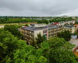 Budynek rehabilitacyjny otoczony zielenią, z widokiem na miasto i stadion.