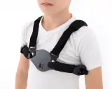 Dziecko w białej koszulce nosi czarny stabilizator klatki piersiowej, który pomaga korygować wypukłą klatkę piersiową.