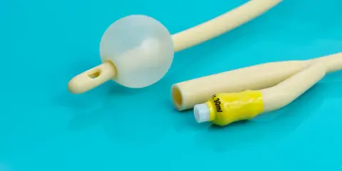 Cewnik Dufour z balonikiem i żółtym znacznikiem 30ml na turkusowym tle.