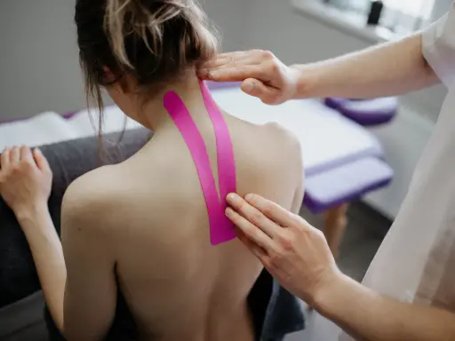 Fizjoterapeuta aplikuje taśmy kinezjotaping na kark pacjentki. Pytanie: czy można masować kręgosłup przy przepuklinie?