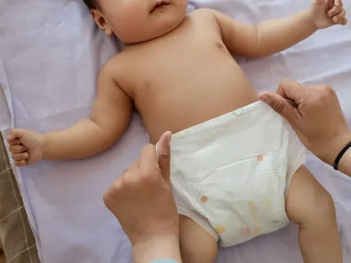 Rączki dziecka leżą na pieluszce, która jest zmieniana. Uważaj na grzybicę pieluszkową.