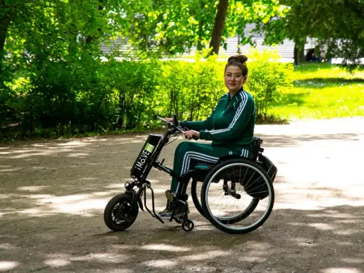 Kobieta w wózku inwalidzkim z napędem elektrycznym, który mógł zostać sfinansowany dzięki dofinansowaniu do wózka inwalidzkiego, cieszy się spacerem w parku.