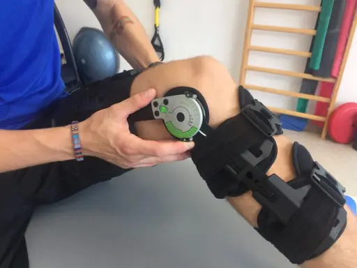 Instrukcja jak założyć ortezę na kolano. Osoba dopasowuje kąt zgięcia na zawiasie ortezy.