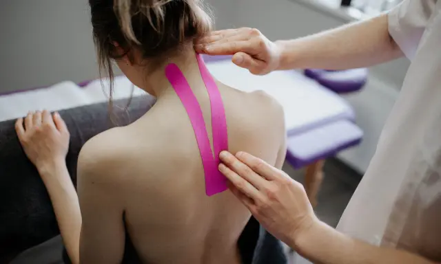Fizjoterapeuta aplikuje taśmy kinezjotaping na kark pacjentki. Pytanie: czy można masować kręgosłup przy przepuklinie?