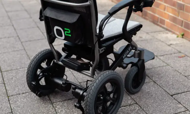 Nowoczesny wózek elektryczny Medilife O2, jeden z wielu rodzajów wózków inwalidzkich, gotowy do jazdy po chodniku.