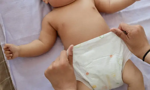 Rączki dziecka leżą na pieluszce, która jest zmieniana. Uważaj na grzybicę pieluszkową.