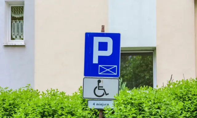 Znak parkingowy dla osób z niepełnosprawnościami, wskazujący 4 miejsca. Informuje o udogodnieniach dla osób z różnymi stopniami niepełnosprawności.