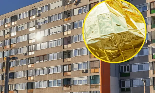 Złota folia NRC, błyszcząca stroną na zewnątrz, odbija słońce od fasady bloku mieszkalnego.