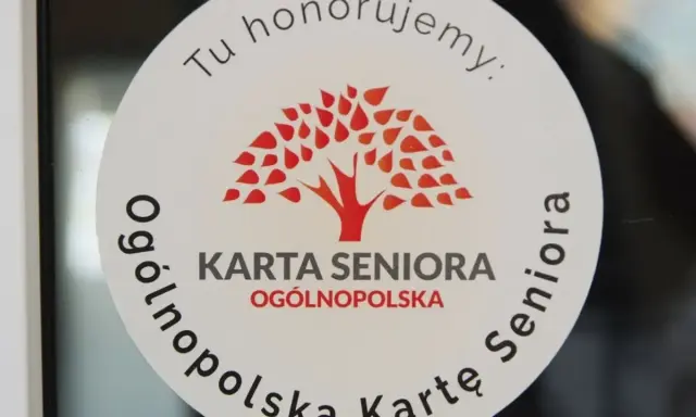 Naklejka z napisem "Tu honorujemy: KARTA SENIORA OGÓLNOPOLSKA" i drzewem. Dostępne zniżki dla posiadaczy ogólnopolskiej karty seniora.