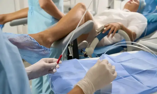 Person w rękawiczkach przygotowuje się do procedury, która może pomóc w oddawaniu moczu po wyjęciu cewnika. Pacjentka leży na łóżku.