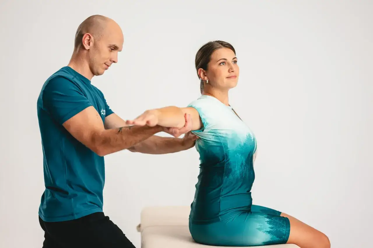 Fizjoterapeuta pomaga kobiecie z krzywą ręką po zdjęciu gipsu, wykonując ćwiczenia rehabilitacyjne.