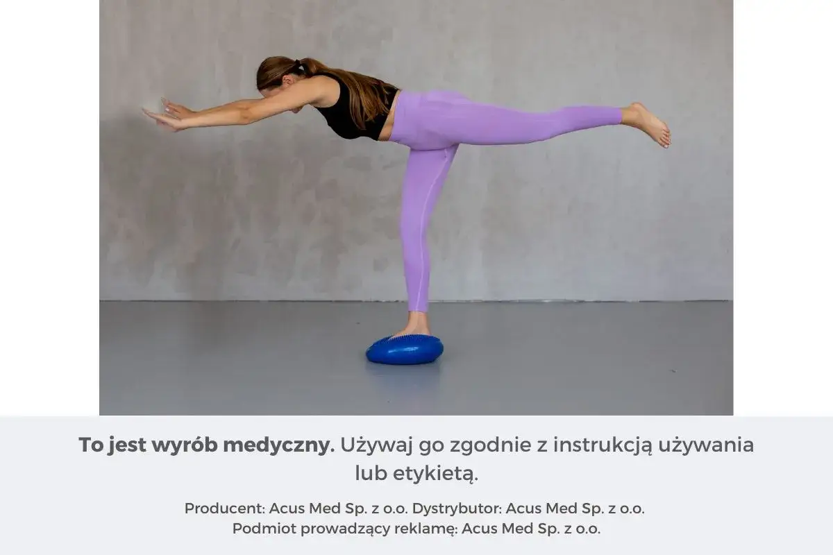 Kobieta wykonuje ćwiczenia propriocepcji na niebieskiej poduszce balansującej, unosząc jedną nogę.